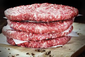 A raw Burger (minced Beef) on dark wooden background